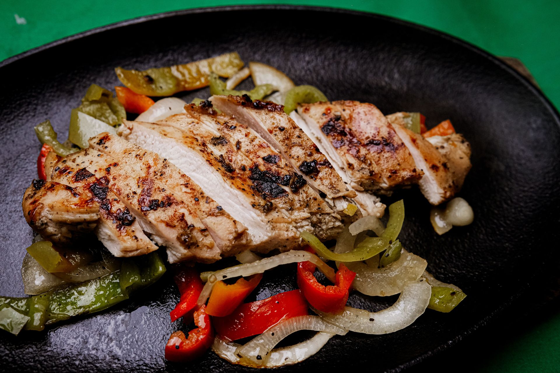 Succulent grilled chicken with vibrant peppers on a sizzling plate, perfect for a tasty meal.